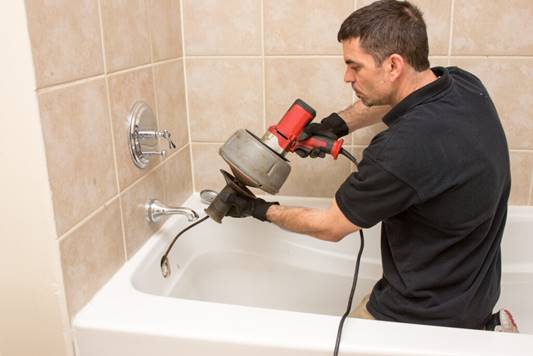 A Milani technician clearing a bathtub drain.